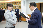 수시인사 임용장 수여식에서 정장을 입은 남성이 회색 맨투맨을 입은 안경 쓴 남성 직원에게 임용장을 전달하는 모습